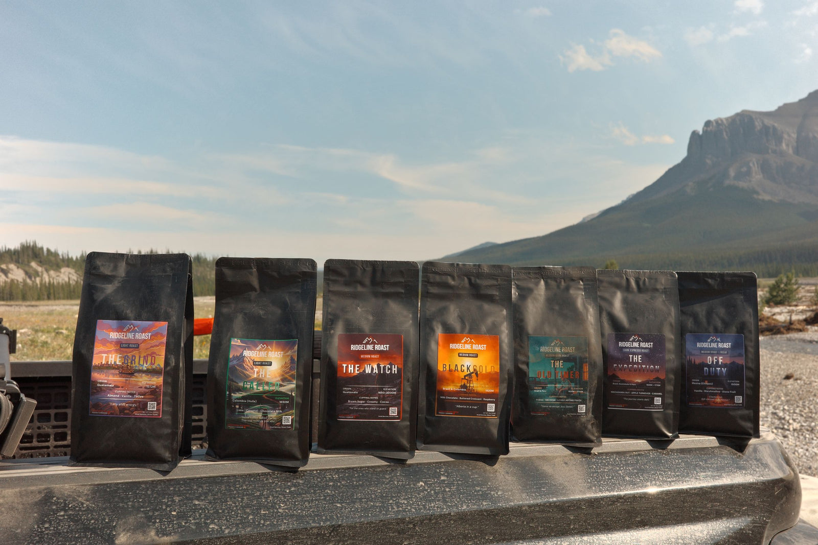 Seven bags of Ridgeline coffee lined up on a truck tailgate in the mountains