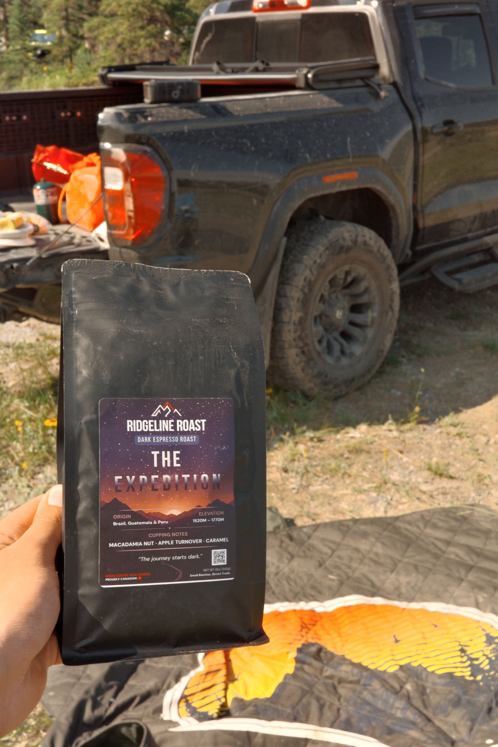 A bag of The Expedition held up in front of a black pickup truck