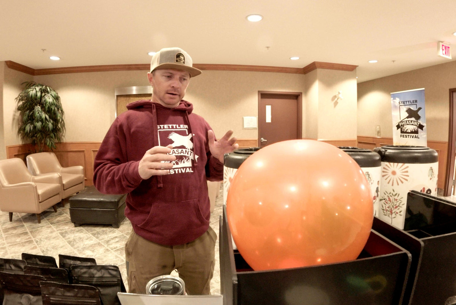 A man in a Stettler Pheasant Festival hoodie with a cup of coffee at the Ridgeline table